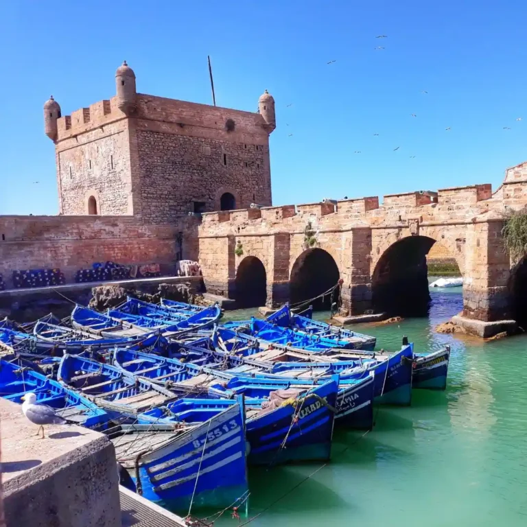Traditional blue fishing boats in Essaouira’s harbor on a bright sunny day, Morocco’s Atlantic coast. Visit Morocco Tours
