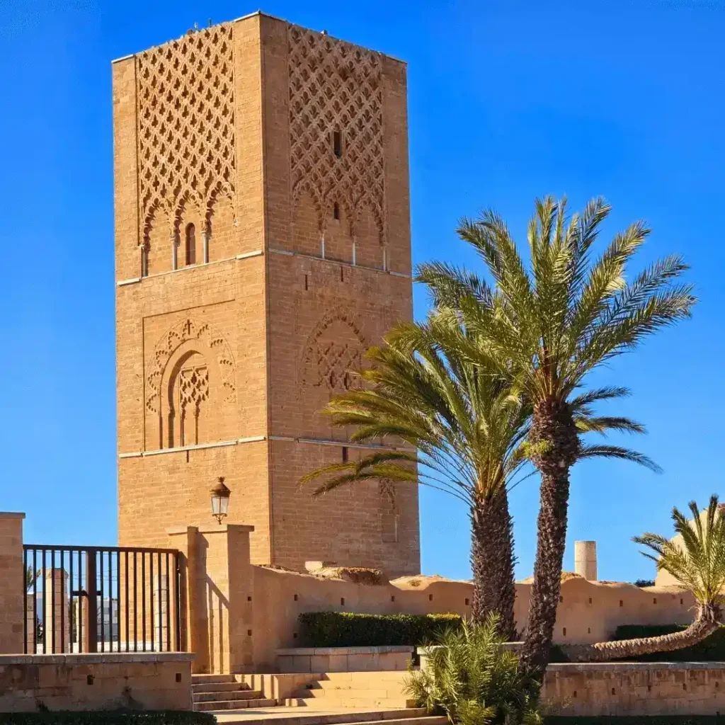 Free things to do in Rabat | Hassan Tower captured from the outer plaza, with visible columns and red sandstone walls. Visit Morocco Tours