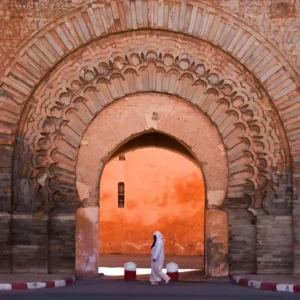 Free things to do in Marrakech | Bab Agnaou Gate with a man in white jellaba walking past its ancient arches. Visit Morocco Tours