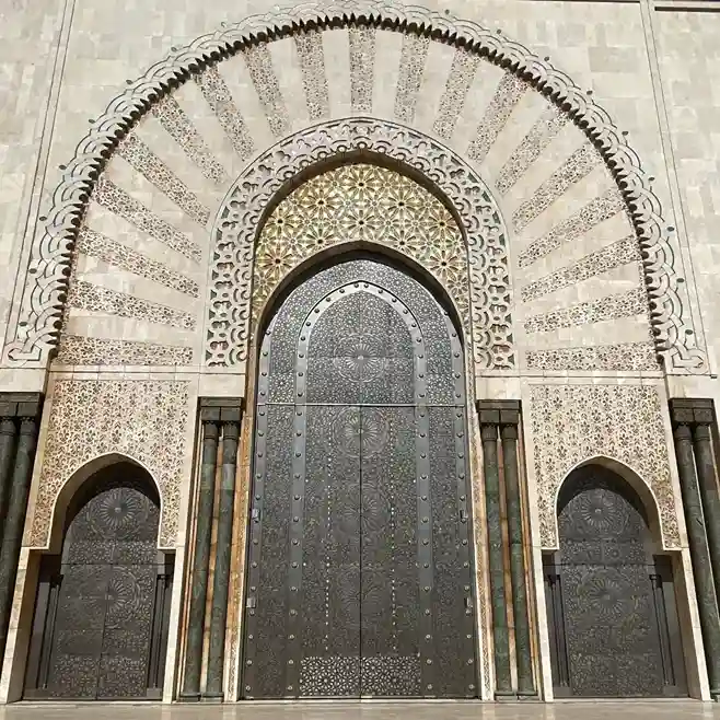 Intricately carved wooden doors and architectural detail at Hassan II Mosque in Casablanca. Visit Morocco Tours