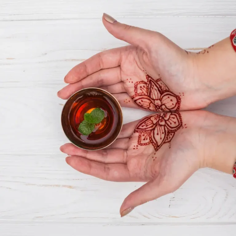 Henna Tattoo Casablanca experience with lady showing intricate designs while holding Moroccan mint tea. Visit Morocco Tours