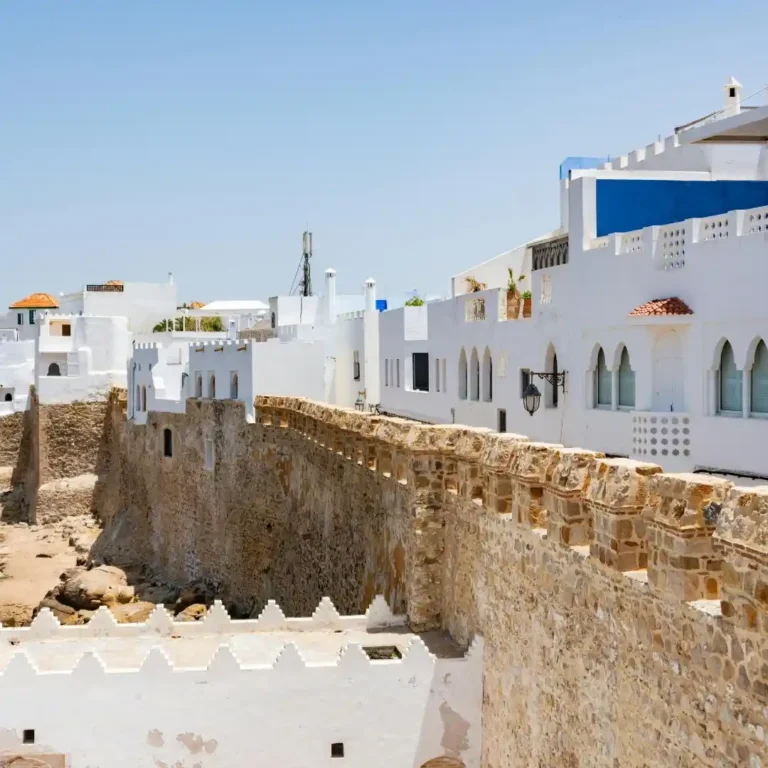 The clean, white-walled streets and vibrant blue accents of the historic Asilah Medina on Morocco's coast. Visit Morocco Tours