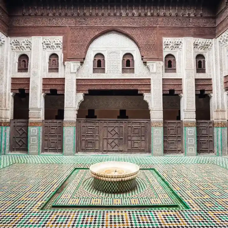 Bou Inania Madrasa Guided Tour: courtyard with intricate Moroccan architecture. Visit Morocco Tours