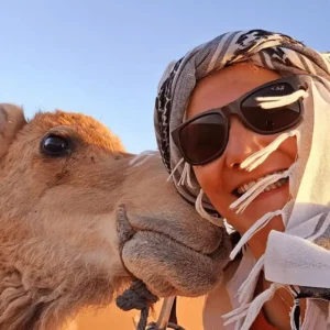A tourist on a camel trek across the golden sand dunes of Erg Chebbi in the Sahara Desert with Visit Morocco Tours.