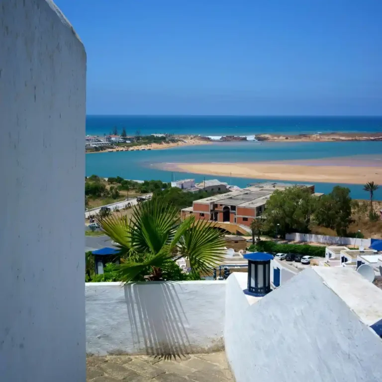 View of the dramatic Atlantic coastline from Oualidia, Morocco, showing where the lagoon meets the ocean on a coastal tour. Visit Morocco Tours